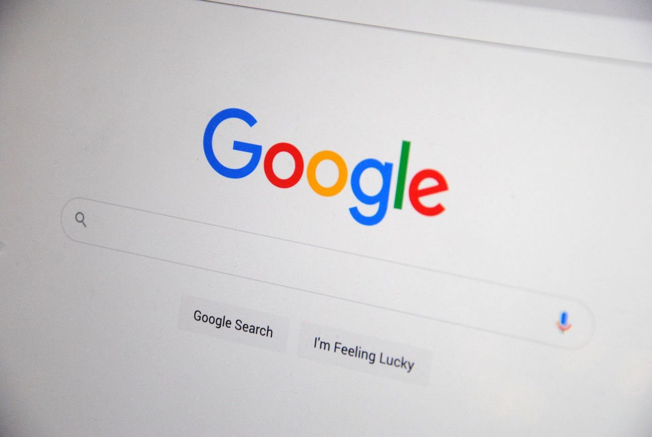 services-04 Close-up of the Google homepage on a screen showing search options.