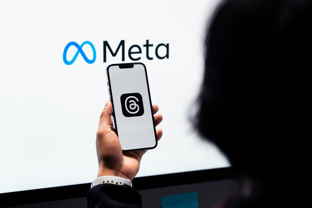 services-02 Hands holding smartphone with Meta Threads logo on screen, Meta branding in background.